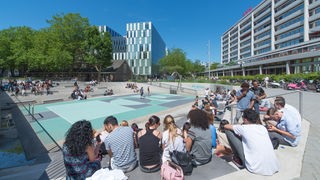 Water Square Benthemplein Rotterdam bei gutem Wetter mit vielen Leuten.