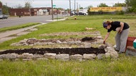 Eine Frau legt auf einem leerstehenden Grundstück in einem armen Stadtteil von Detroit erhöhte Beete an.