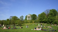 Entspanntes Liegen auf der Schönfeldwiese im Englischen Garten mit dem Monopteros im Hintergrund.