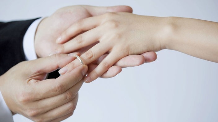 Ein Mann steckt einer Frau einen Ehering auf den Finger.