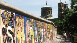 Pärchen spaziert an der Berliner Mauer entlang.