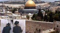 Stadtansicht Jerusalem mit Klagemauer. Davor kleines Bild mit betenden Juden an der Klagemauer