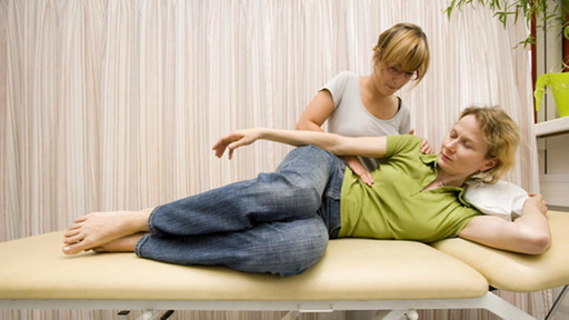 Eine Physiotherapeutin behandelt eine Frau nach dem Bobath-Konzept.