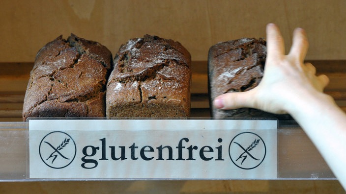 Eine Hand greift nach glutenfreiem Brot