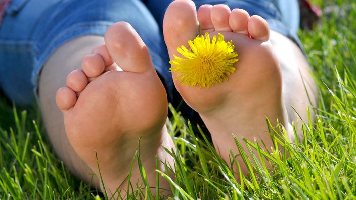 Zwei nackte Füße im Gras.