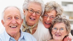 Drei ältere Frauen und ein Senior lachen in die Kamera