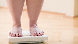 Übergewichtige Frau steht auf einer Waage