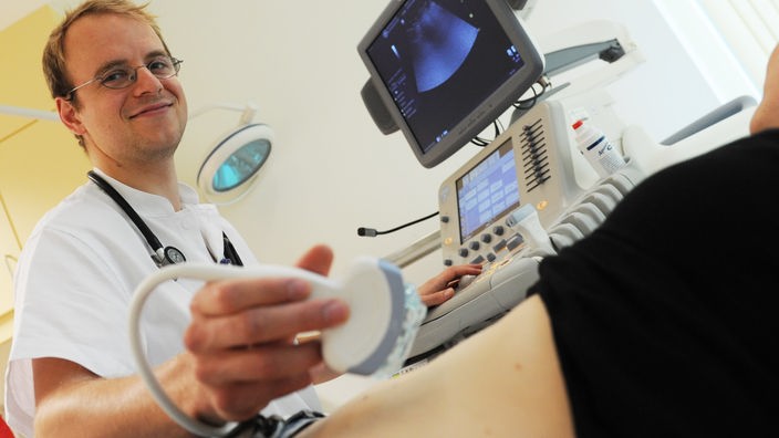 Ein Arzt untersucht den Bauch einer Patientin mit dem Ultraschall