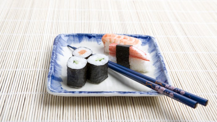 Ein Teller mit japanischem Sushi und Essstäbchen.