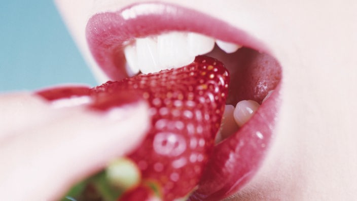 Lippen, die in eine Erdbeere beißen