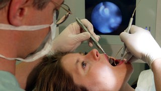 Eine Frau wird vom Zahnarzt untersucht.