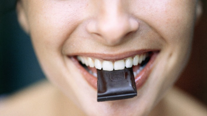 Eine Frau beißt in ein Stück Schokolade