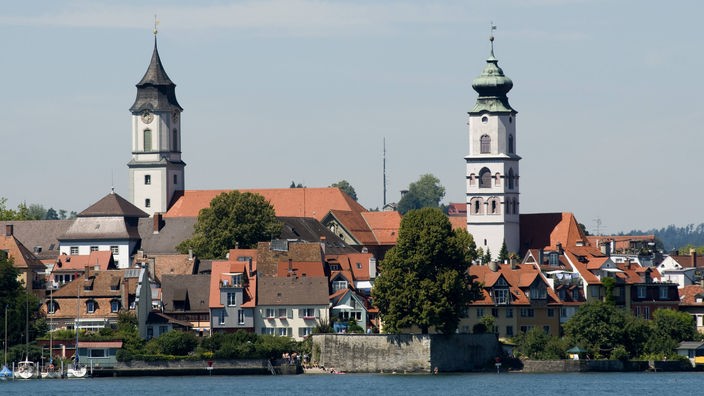 Blick vom See auf zwei Kirchtürme in Bregenz