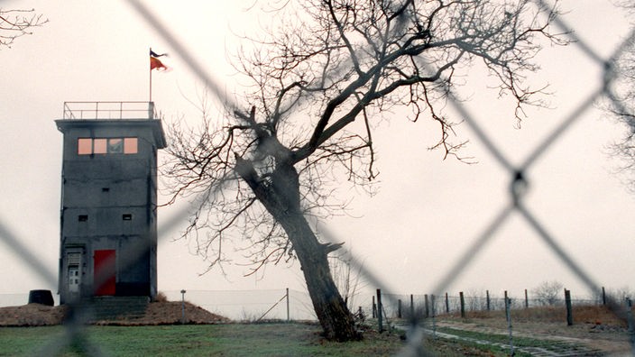 Auf einem flachen Hügel in Rüterberg steht ein Wachturm. Im Vordergrund ist ein Zaun zu sehen.