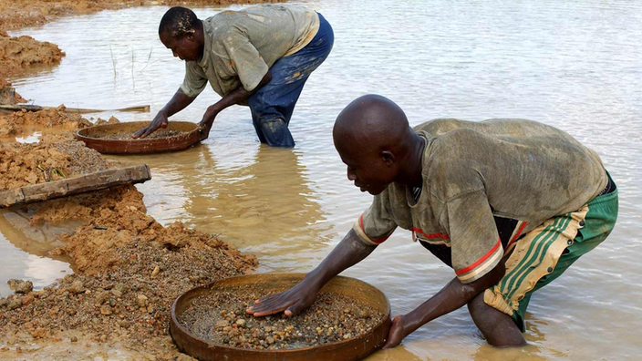 Zwei Arbeiter stehen im Fluss und sieben Sand nach Rohdiamanten. | Bildquelle: dpa Picture-Alliance/Thomas Schulze Zwei Arbeiter stehen im Fluss und sieben Sand nach Rohdiamanten.