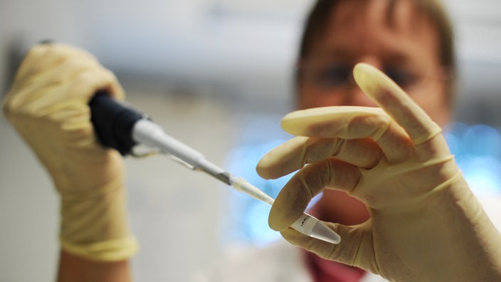 Das Bild zeigt einen Labormitarbeiter beim Pipettieren von DNA-Lösung.