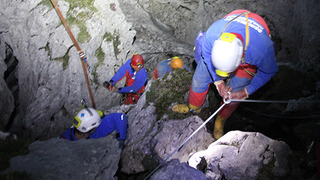 Helfer seilen sich in den steilen dunklen Schacht der Riesendinghöhle ab