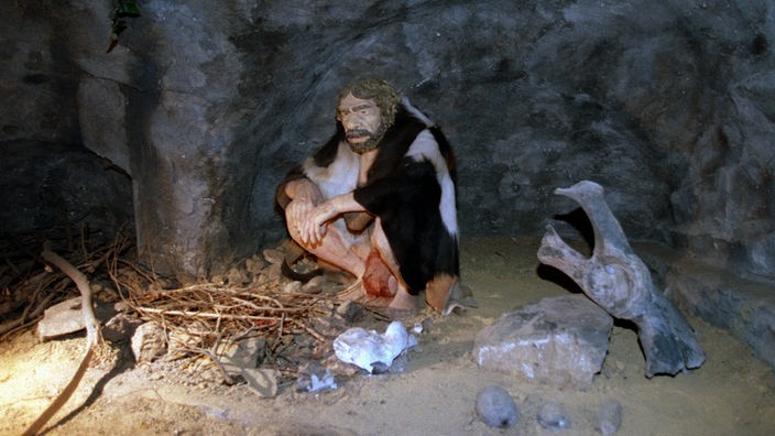 Ein lebensecht nachgebildeter Neandertaler an einer Feuerstelle im Neandertal-Museum.