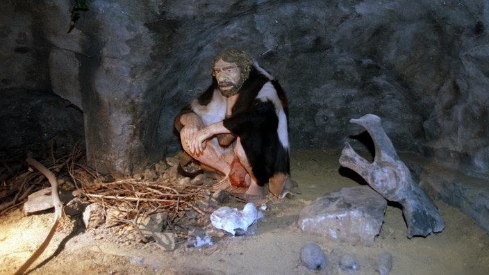Ein lebensecht nachgebildeter Neandertaler an einer Feuerstelle im Neandertal-Museum. | Bildquelle: dpa/Roland Scheidemann Ein lebensecht nachgebildeter Neandertaler an einer Feuerstelle im Neandertal-Museum.