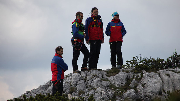 Vier Helfer stehen am Berggipfel auf einem Felsen in der Nähe der Riesendinghöhle