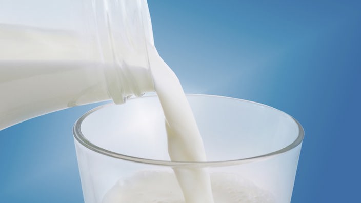 Milch wird aus einer Flasche in ein Glas gegossen.