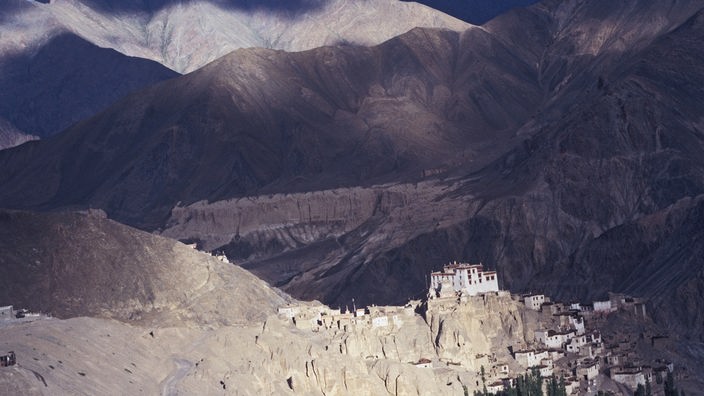 Kloster an einem kargen Berghang. Im Hintergrund die braun gefärbten Berge des Karakorum.