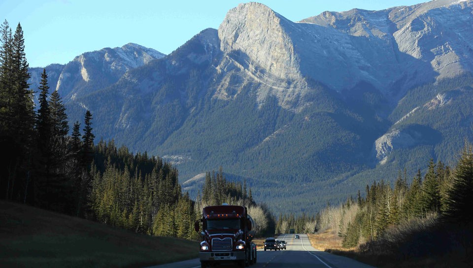Die beeindruckende Berglandschaft im Jasper Nationalpark durch die eine Straße mit einem kleinen Fahrzeug darauf führt ( Alberta, Kanada).