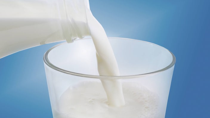 Frische Milch wird in ein Glas gegossen.