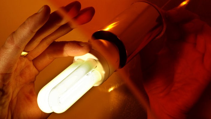 Eine Hand hält eine Energiesparlampe.