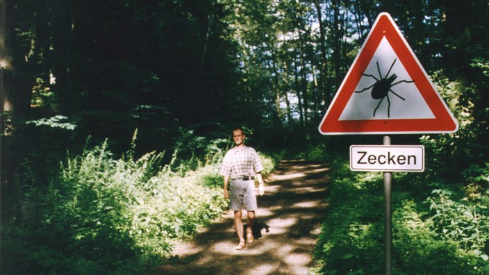 Ein Schild warnt an einem Waldweg vor besonders häufigem Zeckenvorkommen