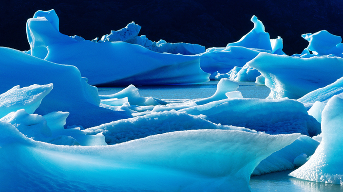 Blau leuchtendes Gletschereis bei Nacht