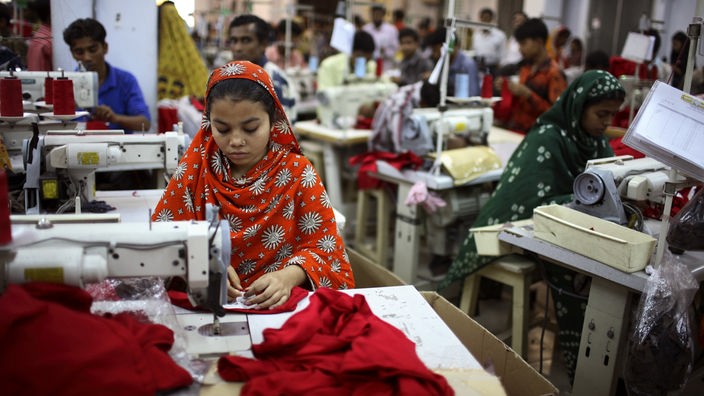 In einer Fabrik in Dhaka in Bangladesch sitzen Menschen an Nähmaschinen.
