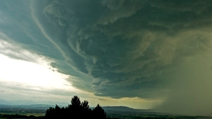 Ein Gewitter schiebt sich als Wolkenwand über eine Landschaft