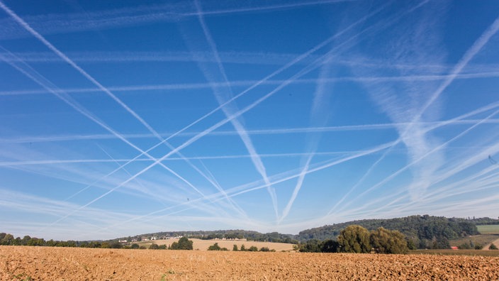 Mehrere Kondensstreifen sind am blauen Himmel zu sehen. | Bildquelle: newspixx vario images/Susanne Baumgarten Mehrere Kondensstreifen sind am blauen Himmel zu sehen.