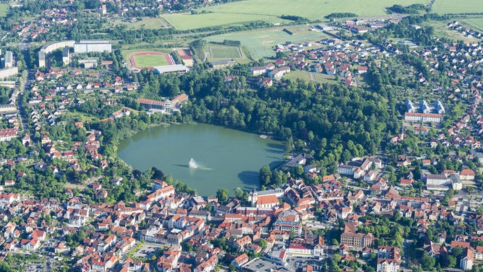 Luftbild eines runden Sees, umgeben von einer Stadt