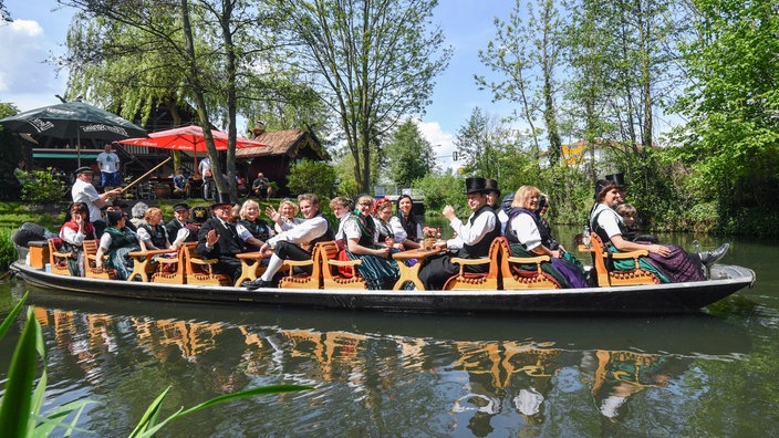 Ein Boot mit Ausflüglern in traditioneller Tracht fährt über einen kleinen Kanal. | Bildquelle: dpa/Patrick Pleul Ein Boot mit Ausflüglern in traditioneller Tracht fährt über einen kleinen Kanal.