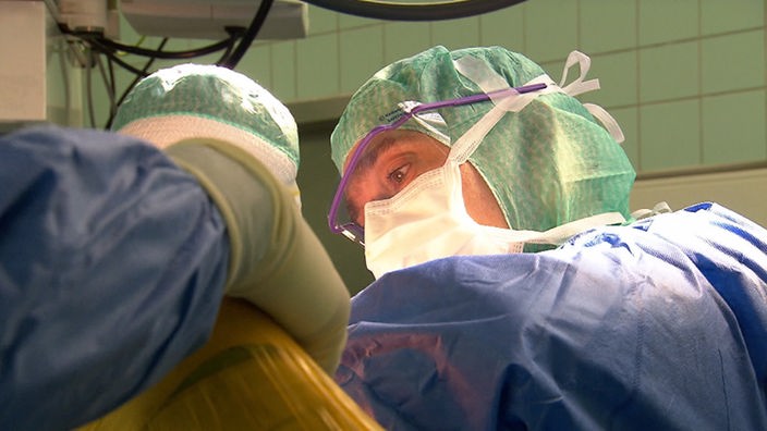 Ärzte in blauen Kitteln und Mundschutz bei einer OP.