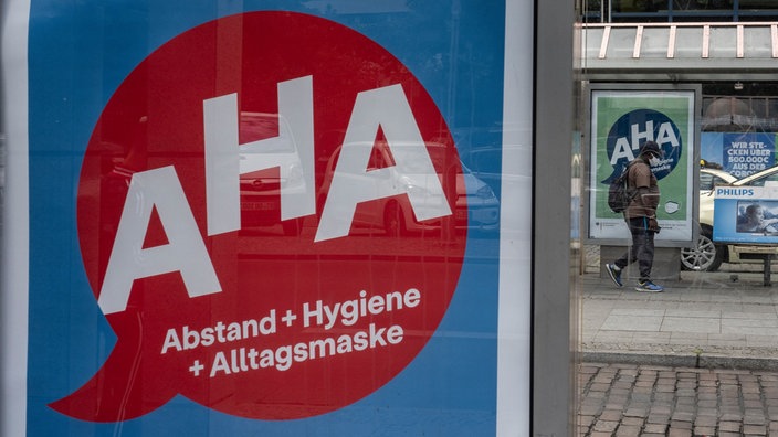 Eine Werbetafel mit der Aufschrift "AHA = Abstand + Hygiene + Alltagsmaske" an einer Bushaltestelle | Bildquelle: WDR / picture alliance/dpa Eine Werbetafel mit der Aufschrift "AHA = Abstand + Hygiene + Alltagsmaske" an einer Bushaltestelle