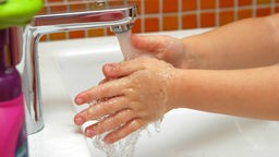 Person wäscht sich die Hände an einem Waschbecken.