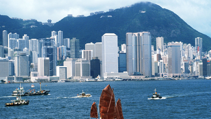Die Skyline von Hongkong vom Wasser, davor ein traditionelles, chinesisches Boot
