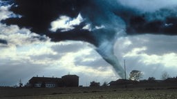 Bild eines Tornados, der einem Haus bedrohlich nah kommt.