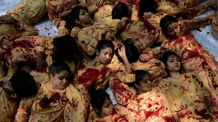 Das Bild zeigt eine Aktion der Tierrechtsorganisation PETA gegen die Lederproduktion. Frauen liegen dicht gedrängt und übereinander auf dem Boden. Ihre hautfarbenen Kleider sind mit Kunstblut überströmt.