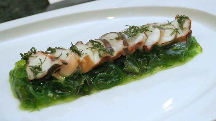 Wakame Seegras Salat mit Krakenscheiben auf einem Teller.