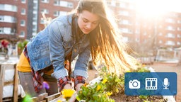 Eine Frau beplanzt ein Hochbeet