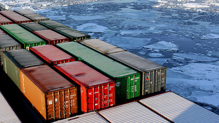 Containerschiff im Polarmeer, auf dem einzelne Eisschollen schwimmen.