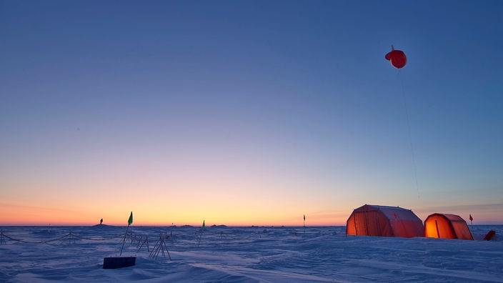 Orange Zelte mit Wetterballon im Sonnenuntergang der Arktis