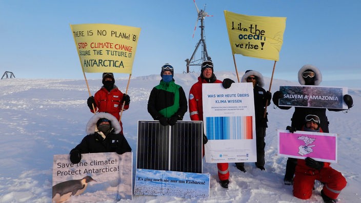 Forscher der Neumayer Station in der Antarktis mit Plakaten