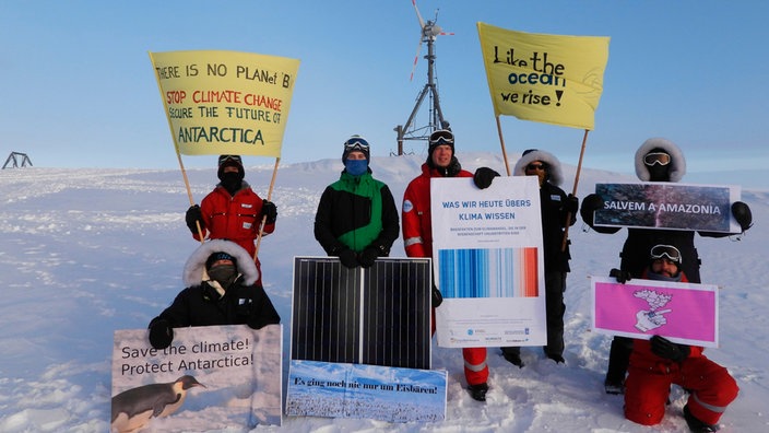 Forscher der Neumayer Station in der Antarktis mit Plakaten | Bildquelle: picture alliance/dpa/AWI Forscher der Neumayer Station in der Antarktis mit Plakaten