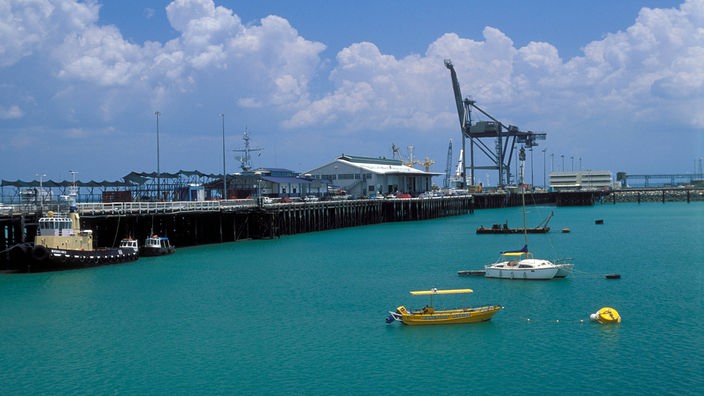 Hafengebiet in der australischen Stadt Darwin mit Anlegestellen, Kränen und Schiffen.
