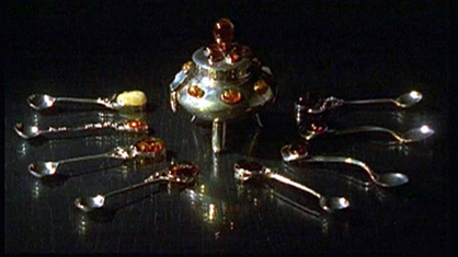 Acht mit Bernsteinen geschmückte Silberlöffel liegen im Halbkreis vor einer Zuckerdose, die ebenfalls mit Bernsteinen verziert ist.